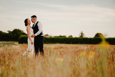 Bride and groom during sunset in a field share a kiss at the night yard