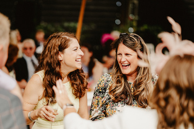 2 female wedding guests are laughing and joking at winters barns in natural light