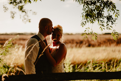 Groom kisses his bride lovingly on the forehead during sunset at Marleybrook House