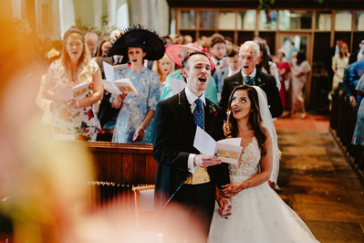 Bride and groom holding each other while singing a hymn in Brenchley church in Kent