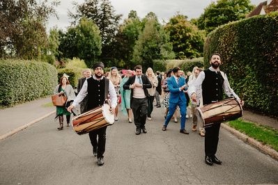 Indian drummer procession leading wedding guests up a residential street to the wedding reception in Kent