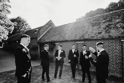 black and white candid wide angle photo of groomsmen outside the night yard