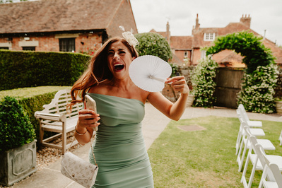 female wedding guest in green dress laughing after nearly falling over at winters barns