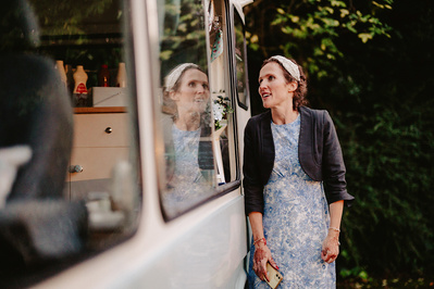 Woman waiting for the ice cream van to open with her reflection in the window in a garden wedding in Kent