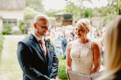 Wedding ceremony with the bride and groom with the wedding guests behind them at Marleybrook House