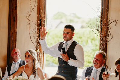 groom reading his speech off a white piece of paper at winters barns with light behind him