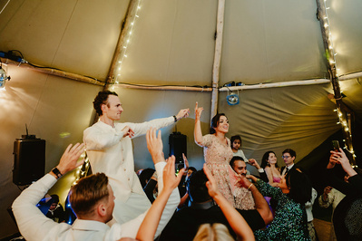 On the dancefloor during this Indian wedding reception the groom and bride are on the wedding guest shoulders during chaos