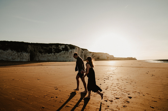 Couple engagement shoot running along the beach during sunset
