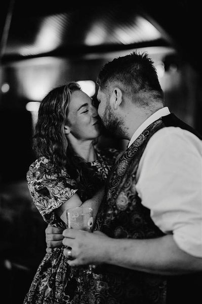 black and white photo of two wedding guests kissing emotionally during the wedding reception