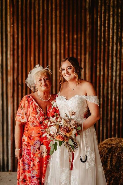 bride and her mother smiling together under the barn roof at silchester farm