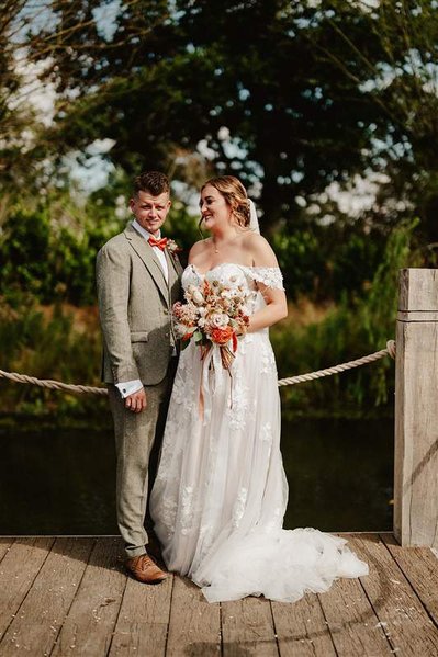 bride and groom standing on a wooden jetty over a lake at silchester farm