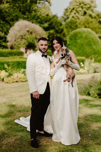 Bride and groom at Broome Park Hotel on their wedding day, holding their dog