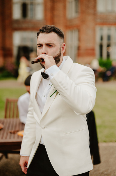 groom at broome park hotel smoking a cigar during the reception