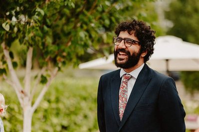 candid photo of a wedding guest smiling in front of greenery 