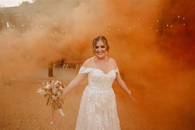 bride holding flowers surrounded by orange smoke from the smoke bombs at silchester farm