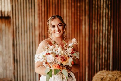 fun portrait of the bride standing in front of a rustic iron barn wall at silchester farm