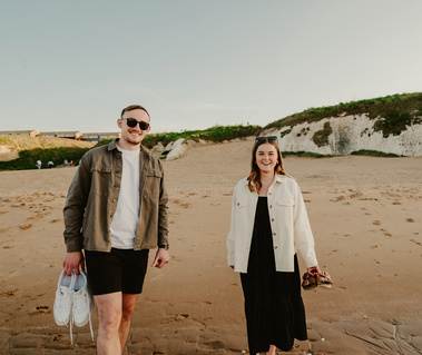 Couple smile at photographer on their engagement shoot at botany bay