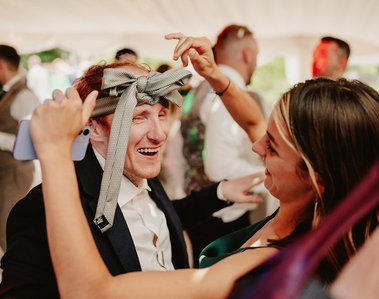 candid photograph of a tie being tied around a wedding guests head at the blazing donkey