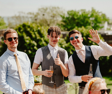 Three men smile and wave to the camera