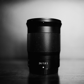 a black and white product photo of the nikkor 24mm f1.8 S on a shelf