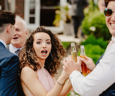 Bridesmaid and Man love looking at the camera holding bottles of beer