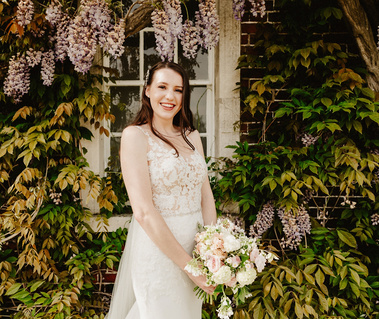 Bridal portrait holding her bouquet in front of flowers
