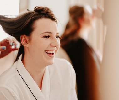 Bride on her wedding day laughing while having her hair done