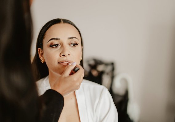 bride having her lipstick applied getting ready before her wedding