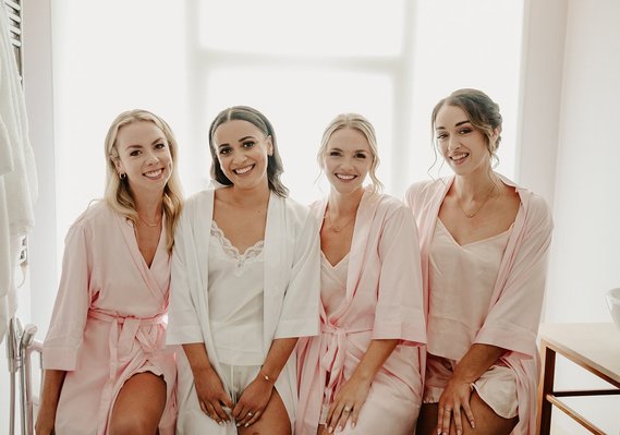 Bride and her bridal party squad sitting in a bathroom for a backlit photo in a hotel room before wedding day