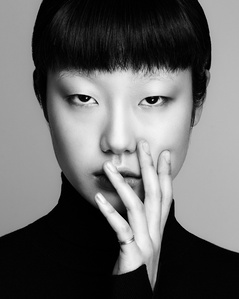 a black and white portrait of an asian female model with a bang and the left hand in front of the mouth 