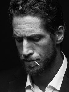 a black and white portrait of the French athlete and actor Emilien de Falco, with a match in his mouth 