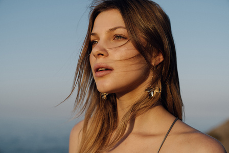 a female model looks towards the horizon during sunrise, with a beautiful warm light at golden hour 