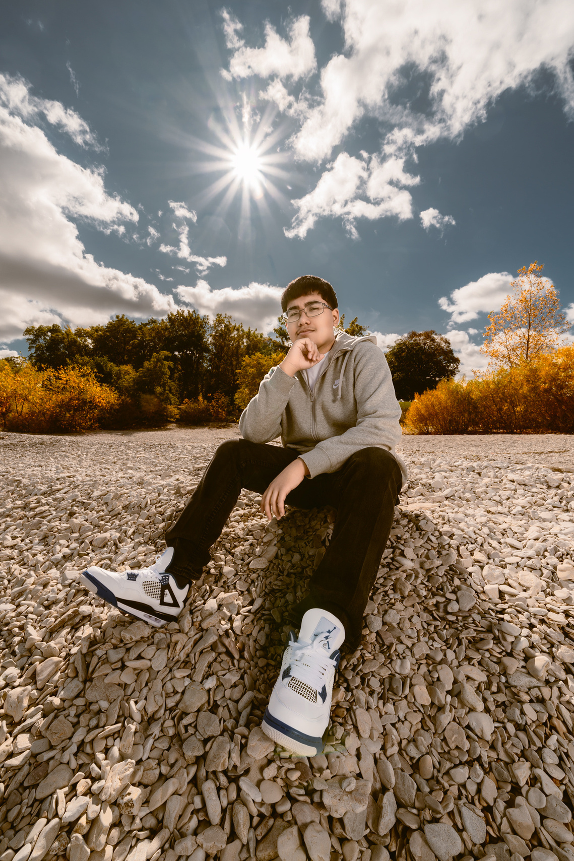A wide angle portrait picture of high school senior boy out in the beach in Mequon Wisconsin. Beautiful autumn colors and shinning sun in the background. 