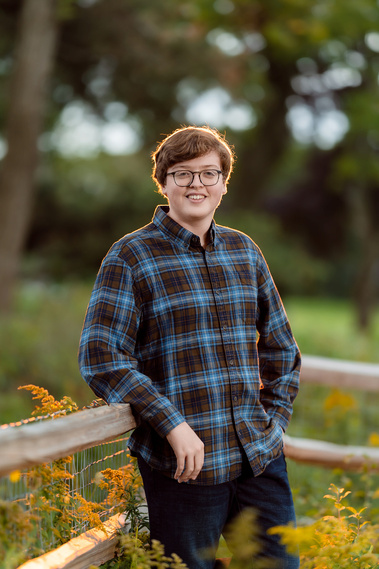 High school senior boy standing against a beautiful sunset backdrop in Mequon, Wisconsin. The warm tones of the setting sun create a perfect atmosphere for this senior portrait.