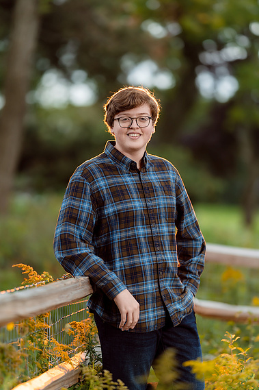 High school senior boy standing against a beautiful sunset backdrop in Mequon, Wisconsin. The warm tones of the setting sun create a perfect atmosphere for this senior portrait.