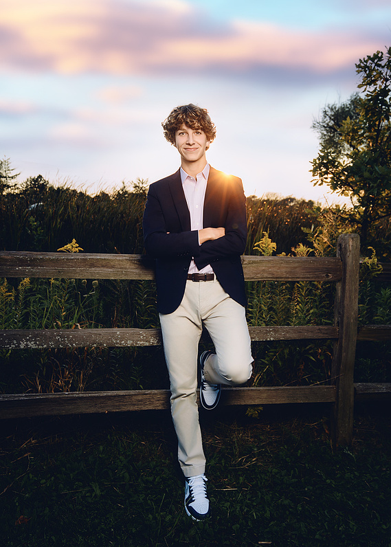 Senior portrait of a young man in a natural setting in Milwaukee, Wisconsin. This outdoor shot highlights his unique style and individuality, framed by lush greenery and autumn foliage. 