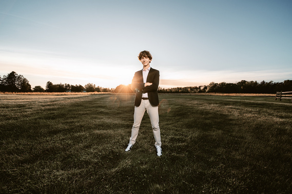 Dynamic senior portrait featuring a high school boy posed in a picturesque park in Mequon, Wisconsin. The image showcases his personality and enthusiasm for future. 