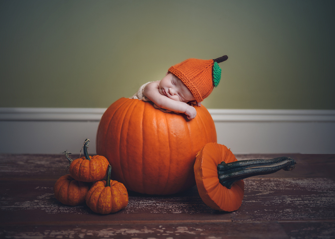 Baby inside a big pumpkin fun newborn photoshoot in Mequon Wisconsin. Creating newborn photography in Mequon WI.