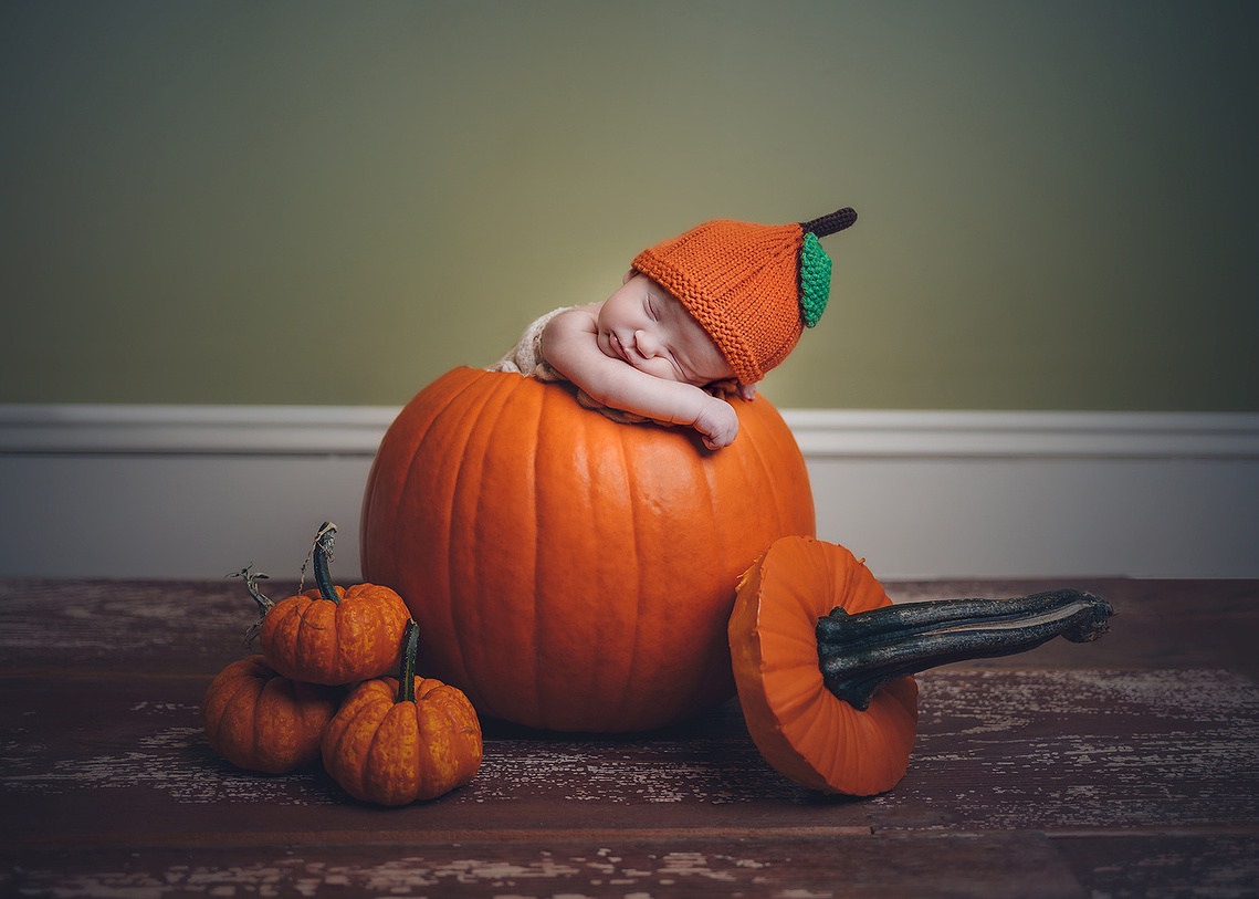 Baby inside a big pumpkin fun newborn photoshoot in Mequon Wisconsin. Creating newborn photography in Mequon WI.
