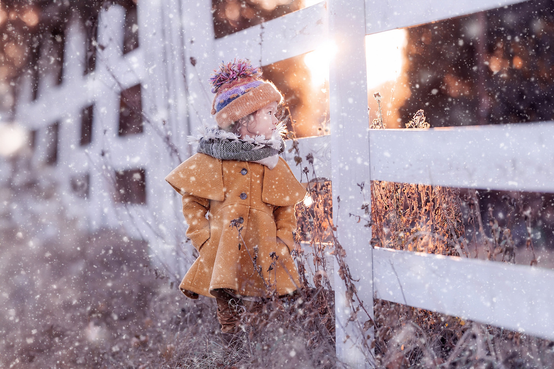 Cute girl starring at the sunset during the snowfall. Outdoor child portrait during the sunset at Cedarburg WI. 