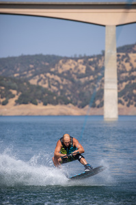 Person landing a jump while wakeboarding behind a boat.