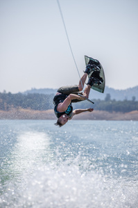 Man doing a backflip while wakeboarding behind a boat.
