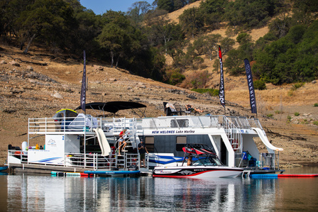 Two house boats in New Melones Lake with a Nautique boat docked on the side.
