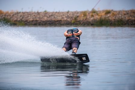 Person wakeboarding while holding onto the handle behind his back.