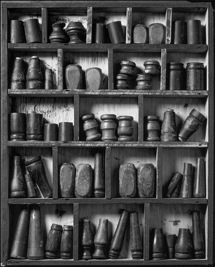 Still life of various objects arranged in a compartmented shelf or box.