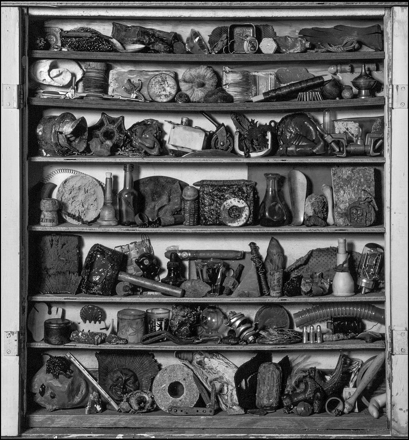 Still life of various objects arranged in an improvised cabinet.