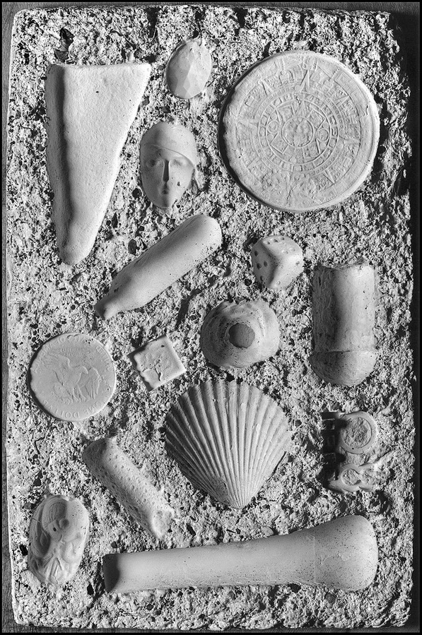 Relief impression of various objects in a slab of plaster.