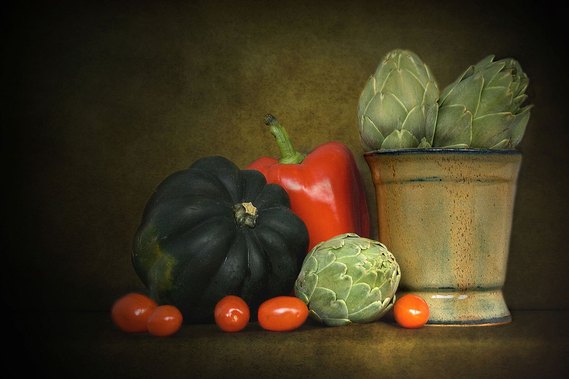 Pottery And Artichokes.  A still life image with pottery by Kate Boivin and photographed by Holly Cawfield using peppers, grape tomatoes and artichokes.  Natural light and multiple textures for the background.