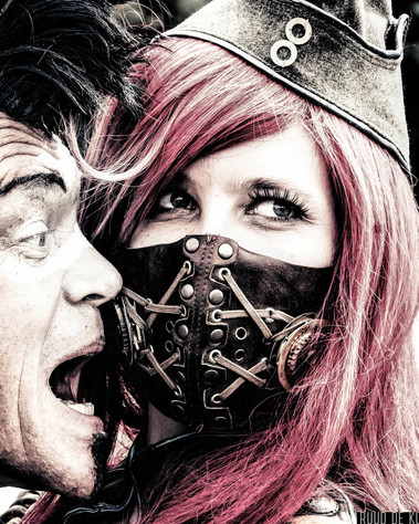 Constance Bashford smiling behin the mask. Post apolcalypse actor very near her face looks like shouting at her.