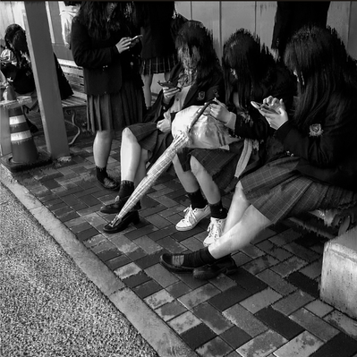 4 students sitting together not interacting with each other while scrolling on their smartphones.